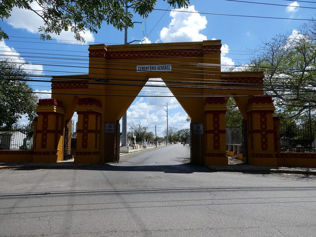 Arche d'entrée jaune et rouge du Cementerio General de Mérida, avec le nom du cimetière en haut, de jour